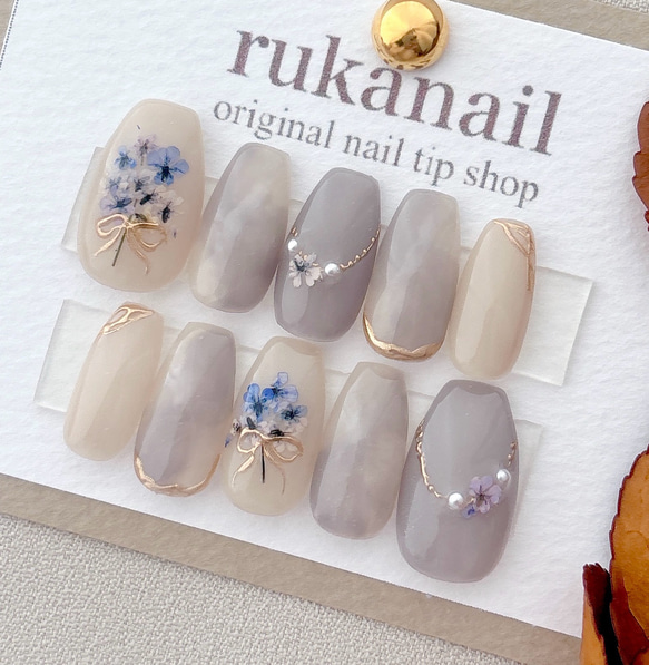 Pressed-flower and muted blue/gray decorative nail tips displayed on a card labeled rukanail.
