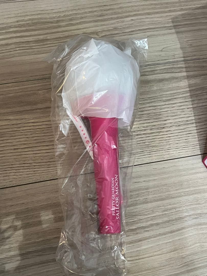 Photo of the 美少女戦士セーラームーン official fanlight pen light (pink) wrapped in clear plastic on a wooden floor.
