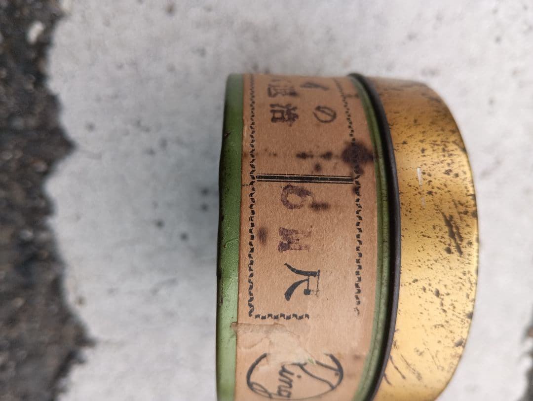 Close-up of the side of a small metal film tin with a Japanese paper label, for a 35mm film roll.