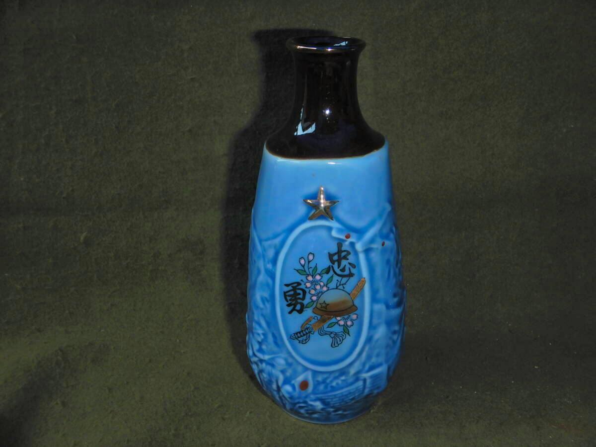 Blue ceramic military tokkuri (sake bottle) with a dark neck, a star emblem, and a painted helmet motif with Japanese characters.
