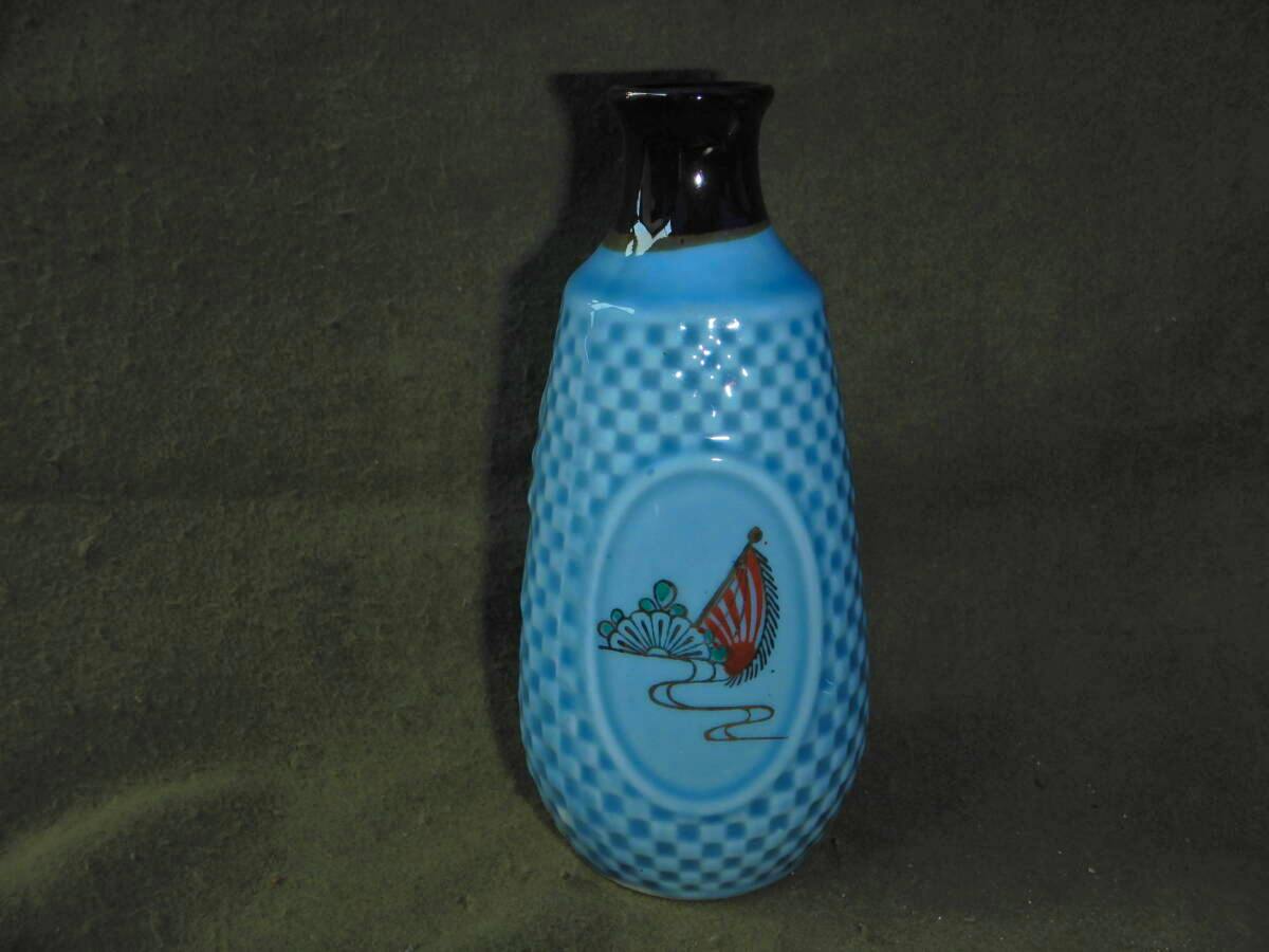 Blue textured ceramic sake bottle (tokkuri) with a black neck and an oval panel showing a red-striped flag and chrysanthemum motif.
