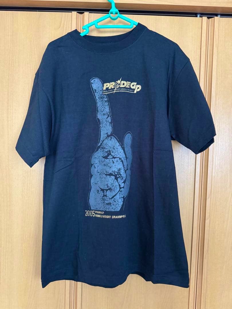 Front view of a black PRIDE GP 2005 men's cotton T-shirt hanging on a hanger, showing a large hand graphic and a small PRIDE GP logo.