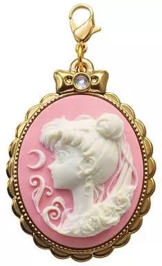Gold-framed oval pink cameo bag charm depicting Princess Serenity's white profile with a crown and a lobster clasp.