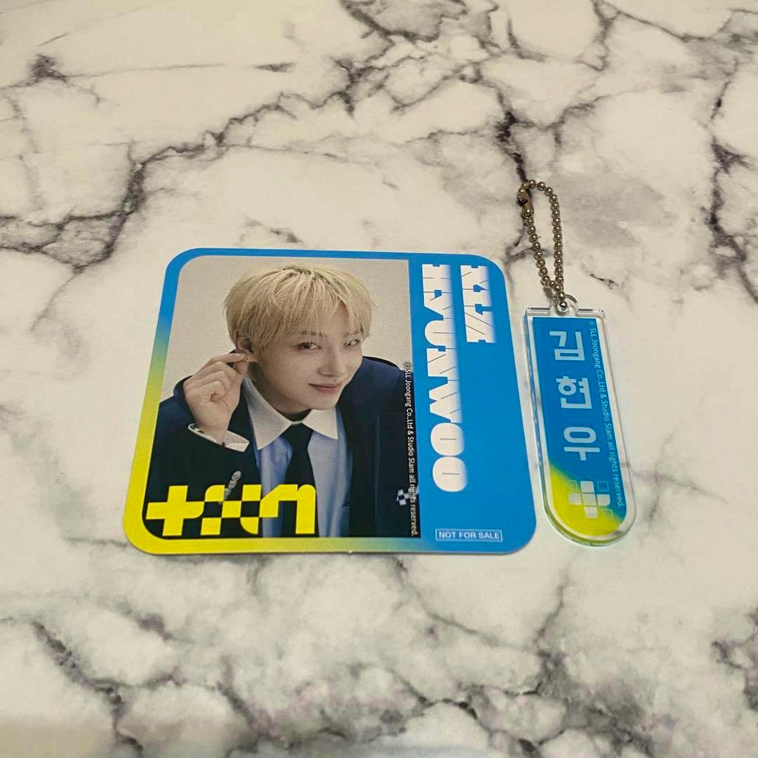 A photo of an acrylic coaster with Kim Hyunwoo's portrait and a matching acrylic keychain with a ball chain on a marble surface.