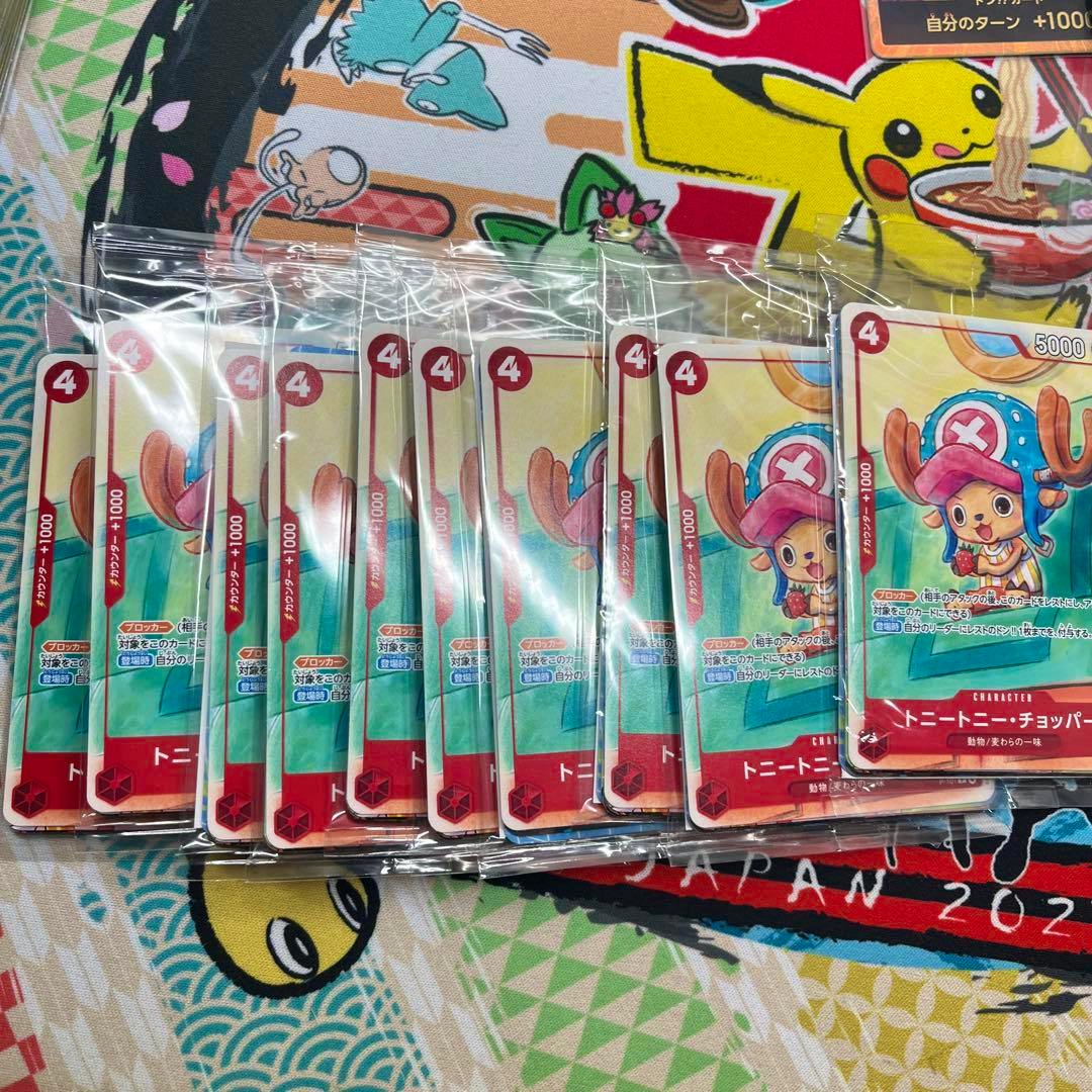 Multiple sealed promotional trading cards showing a cartoon character in a blue hat, laid out in rows on patterned fabric.