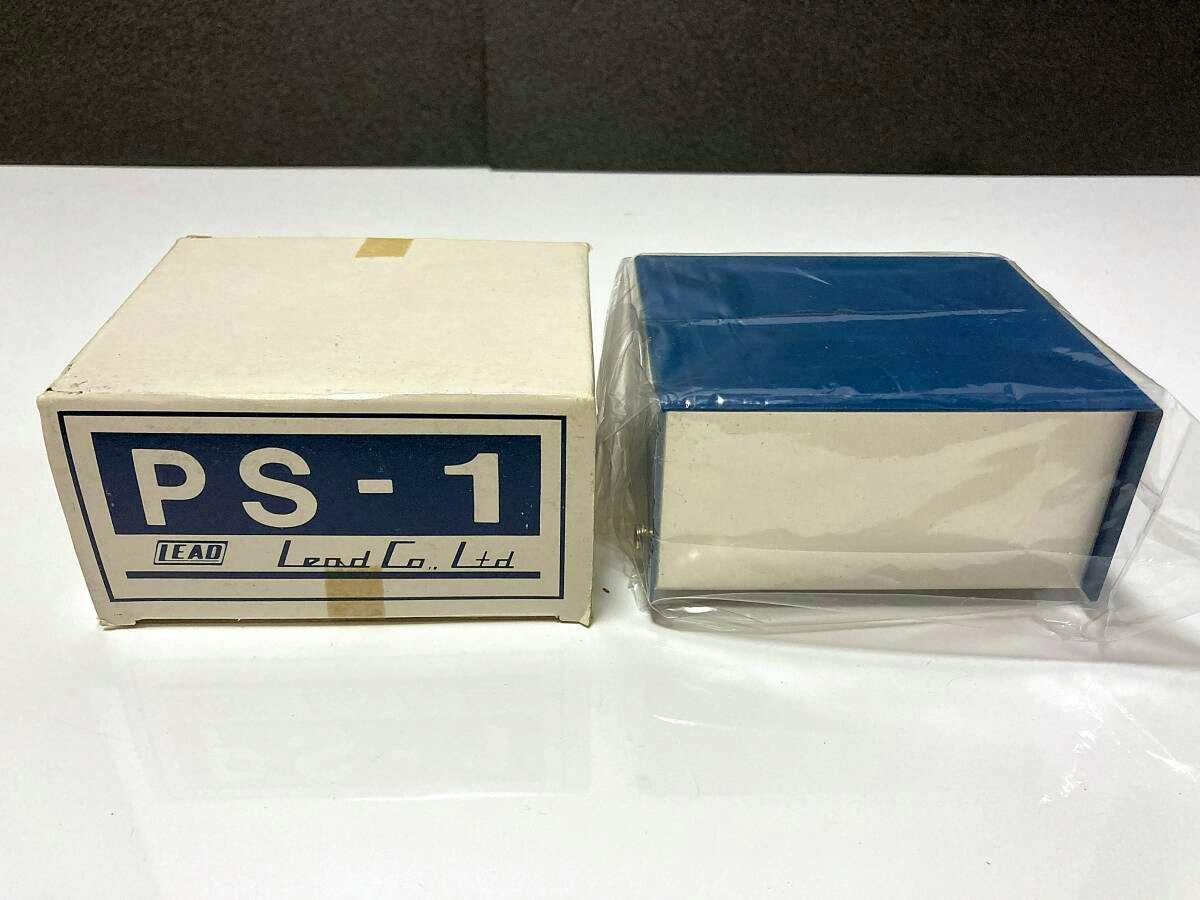 A PS-1 LEAD metal case wrapped in plastic placed beside its PS-1 labeled cardboard box on a white surface.