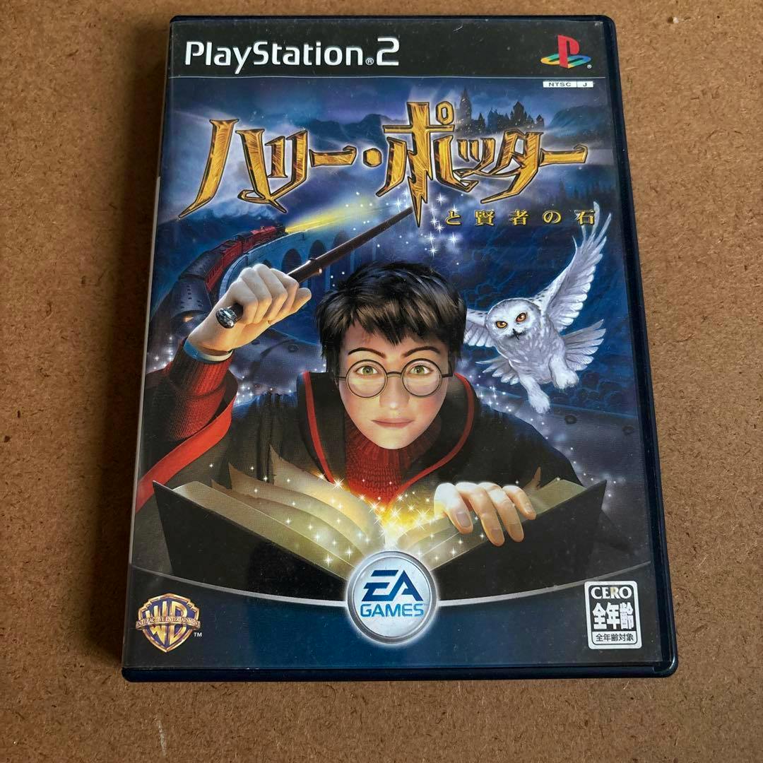 Front cover of the PlayStation 2 game 'ハリー・ポッターと賢者の石' showing an illustrated bespectacled boy holding a wand and an owl.