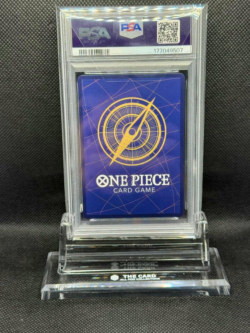 PSA-graded One Piece trading card (back side) in a clear plastic slab displayed on a small stand.