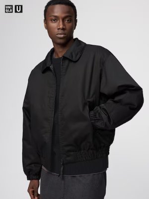 A man modeling a black short blouson men's jacket with elastic hem and a zip front.