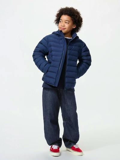 Child model wearing a navy children's polyester puffer washable parka jacket standing against a plain background.