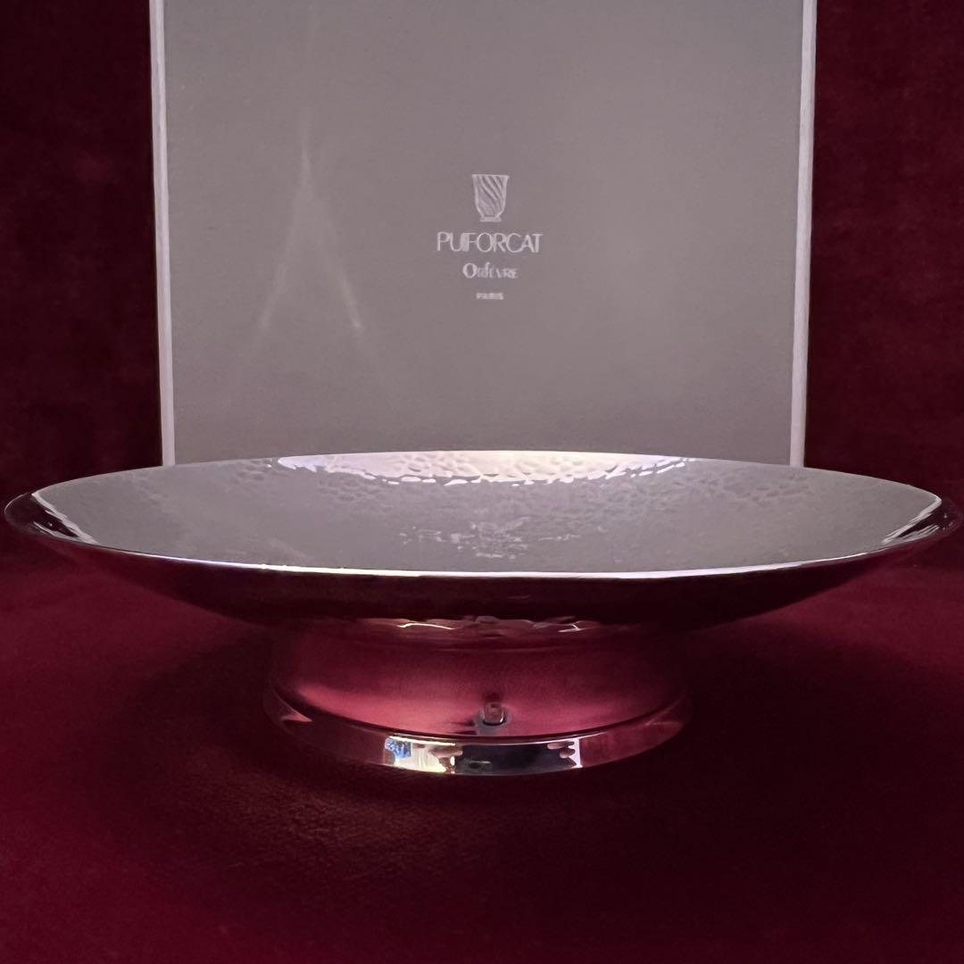 Hammered stainless steel PUIFORCAT "GUERMANTES" pedestal plate shown front-on with its box in the background.