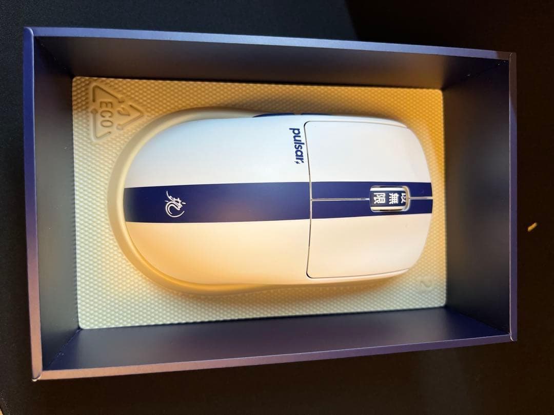 Top-down photo of the pulsar X2 crazy light BRUCE LEE EDITION PC mouse in its box, showing a white mouse with a blue center stripe.