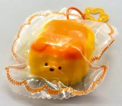 A packaged yellow dog-shaped bread silicone squishy toy with an attached star-shaped clip visible.