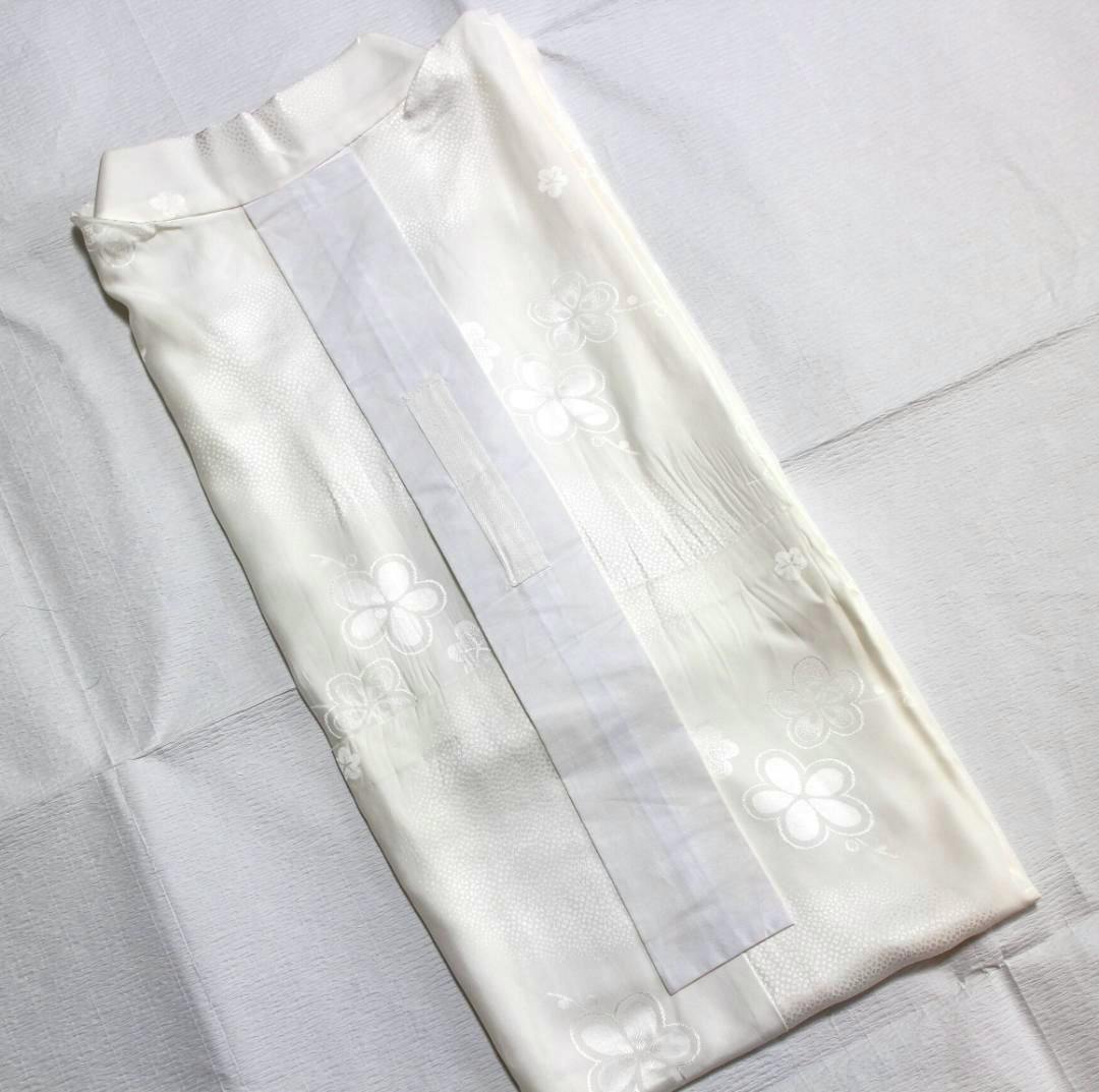 Folded white silk single-layer nagajuban (長襦袢) with a plum blossom pattern laid flat.