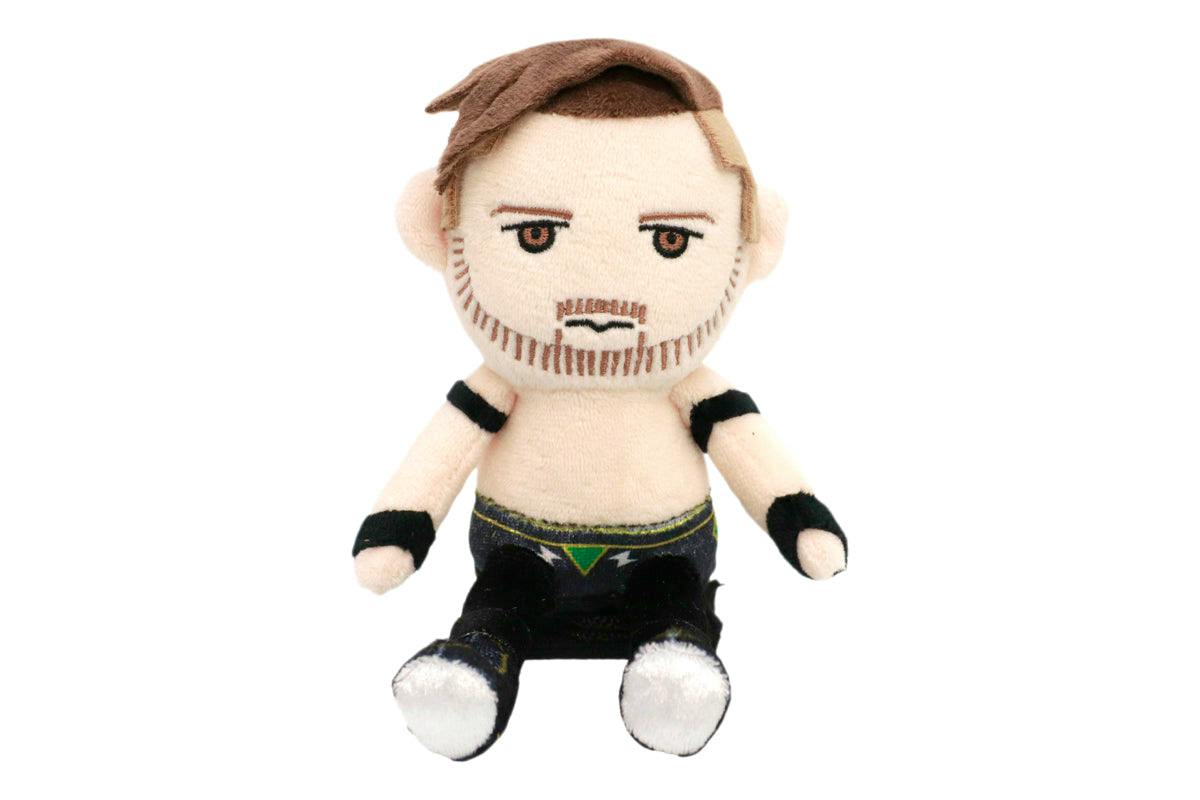 Front view of the ぴょんすけ カラム・ニューマン plush toy showing a seated character with embroidered beard, brown hair, black wristbands, and black pants.