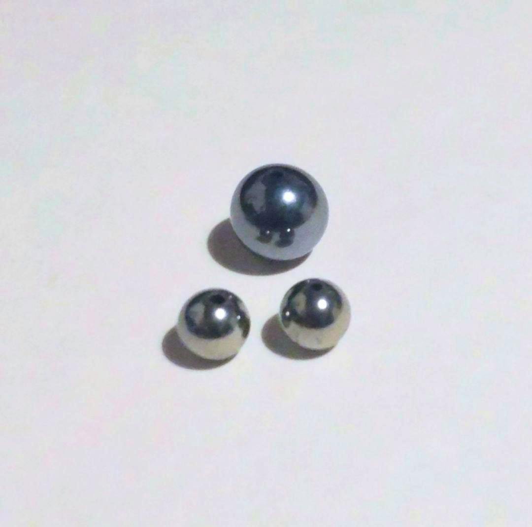 Three round natural stone beads (two small, one larger) shown on a white background.