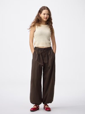 Model wearing dark brown polyester balloon pants with elasticized cuffs and hands in pockets.