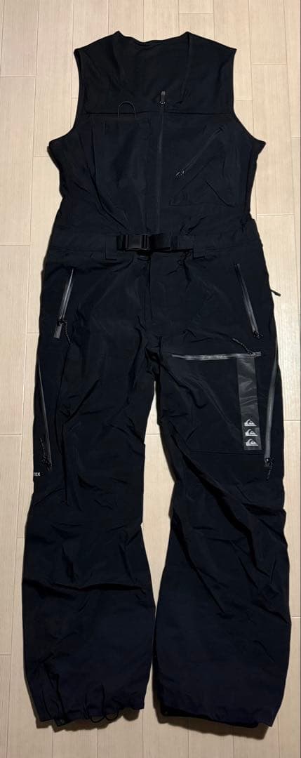 Front view of black Quiksilver HIGHLINE PRO 3L GORE-TEX bib pants laid flat on a light wood floor.