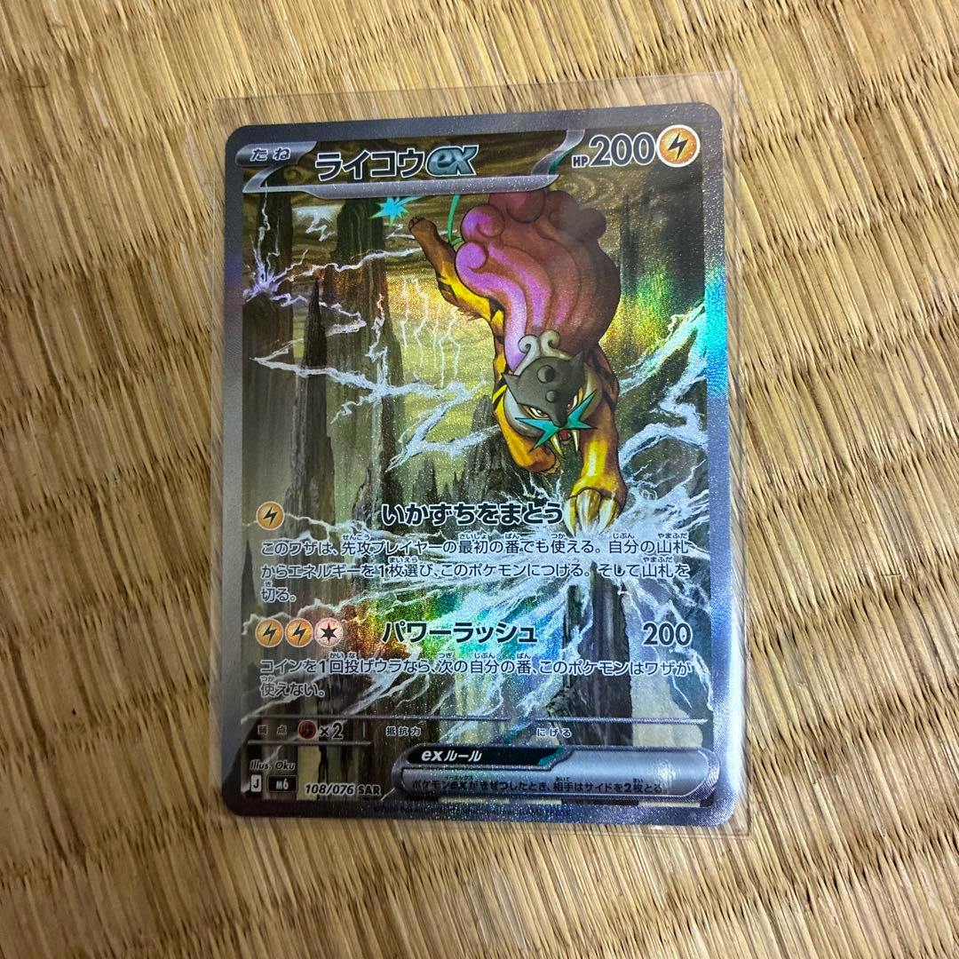 Holographic Japanese ライコウex trading card (108/076 SAR) shown in a protective sleeve on a wooden surface.