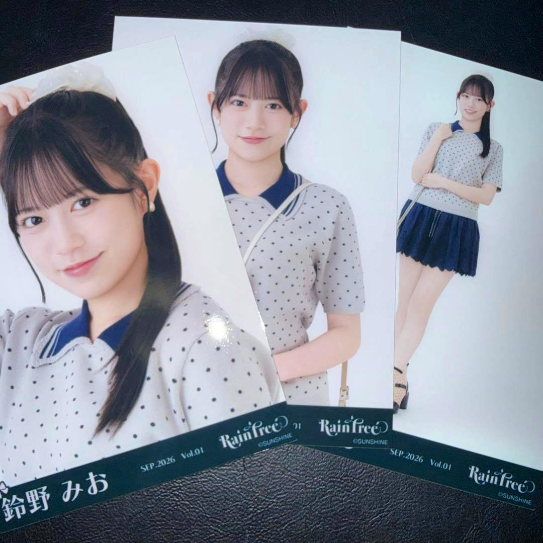 Three photocard prints showing a woman in a light polka-dot top and navy skirt fanned on a dark textured surface.