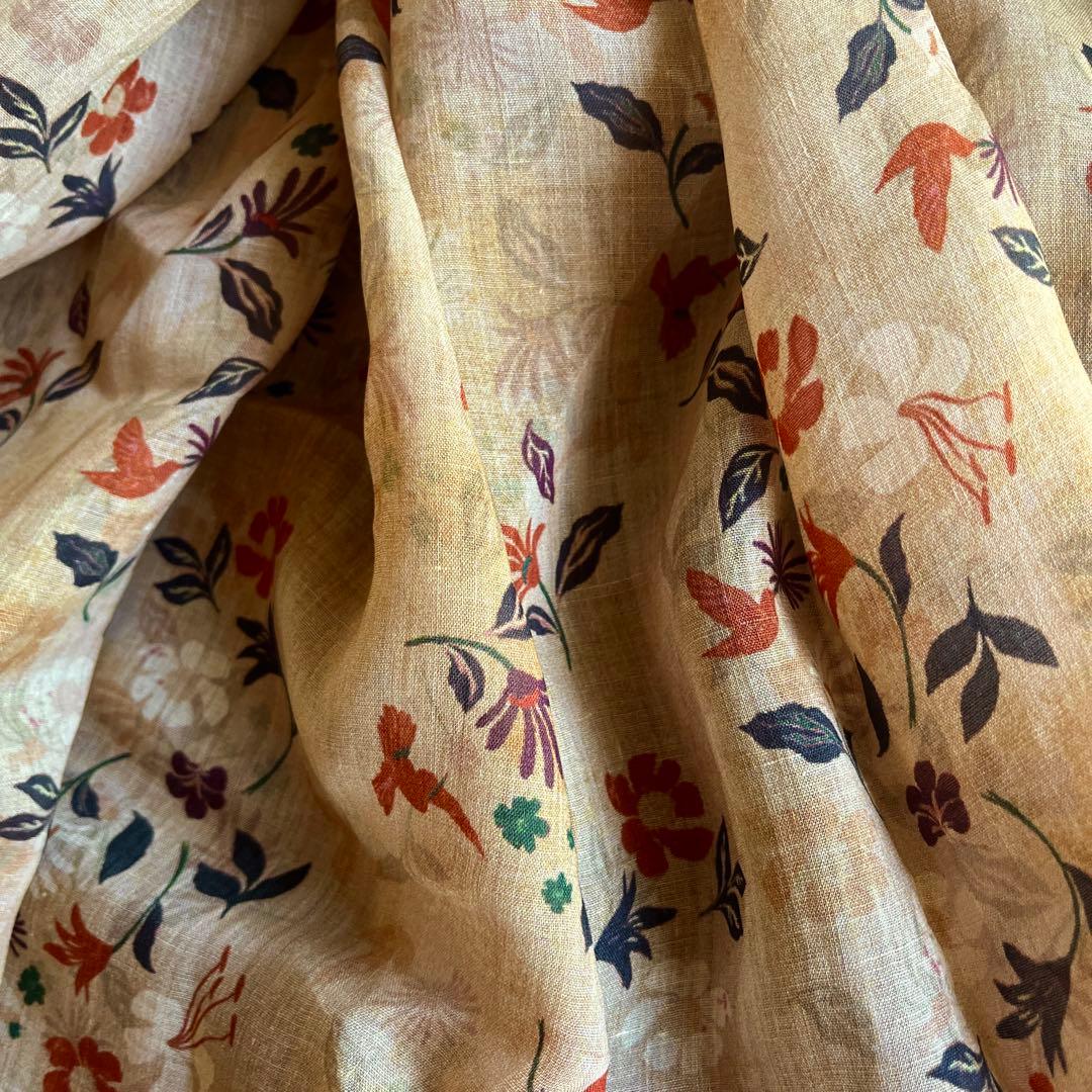 Draped thin light-brown ramie/linen fabric with a multicolored floral print showing texture and pattern.