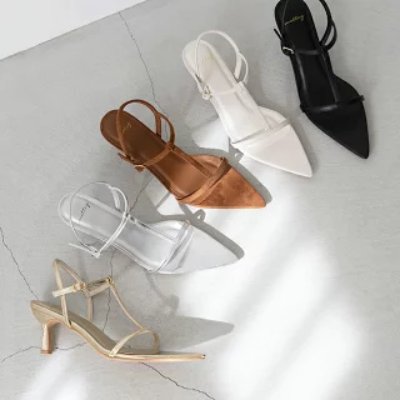 Top-down photo of several pointed-toe ankle-strap synthetic-leather sandals in different colors arranged on a light floor.