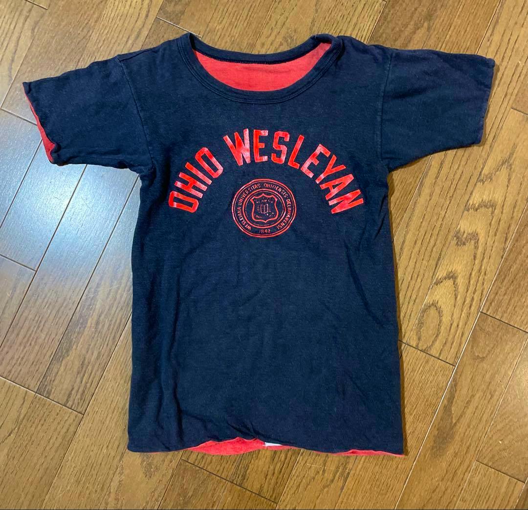Flat-lay navy T‑shirt showing red interior at sleeves and hem with "OHIO WESLEYAN" printed on the front, laid on a wooden floor.