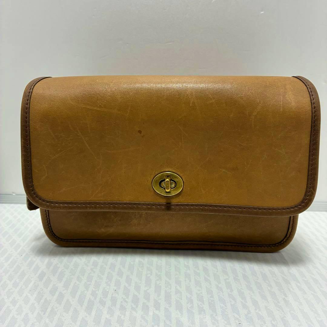 Front view of a vintage tan Coach saddle leather bag showing the flap and brass turn-lock closure.