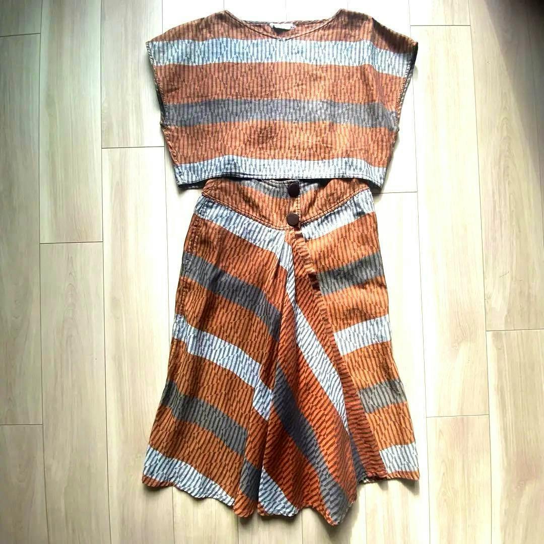 A striped women's shirt and matching skirt laid flat on a wooden floor.