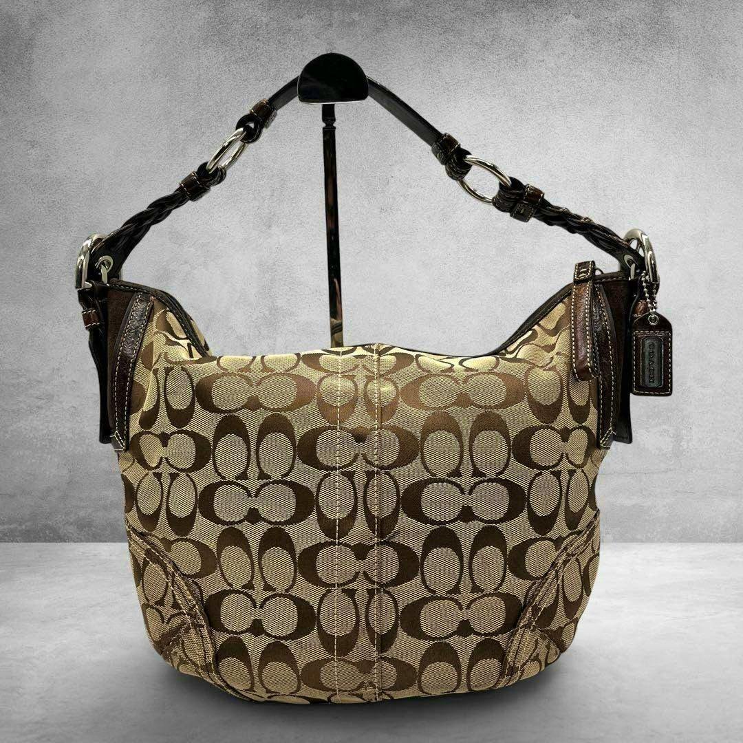 Front view of the Coach signature canvas hobo bag on a stand, showing the braided leather shoulder strap and hanging Coach tag.
