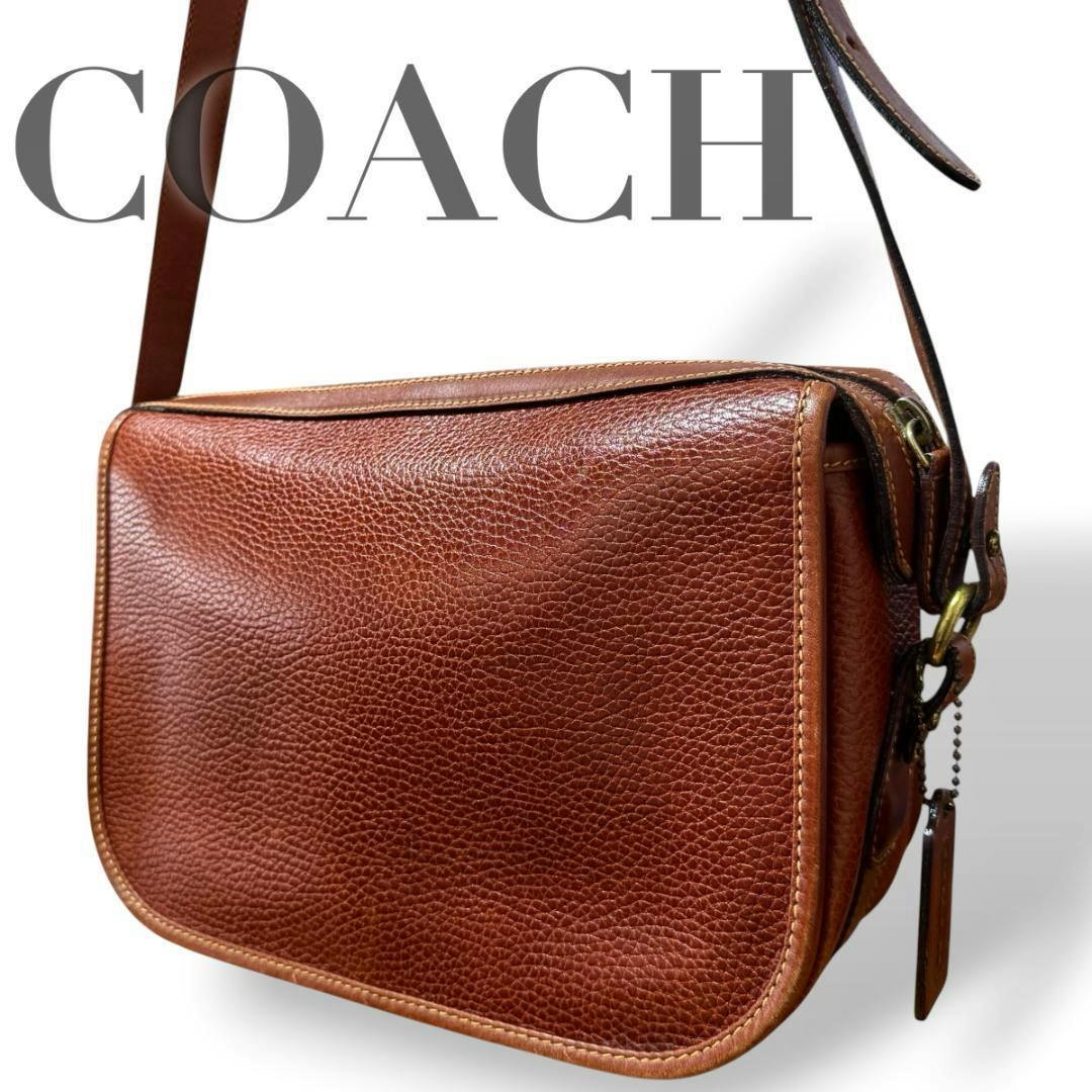 Close-up of the brown pebbled cow leather Coach shoulder bag showing the front panel, top edge, shoulder strap, and metal hardware.