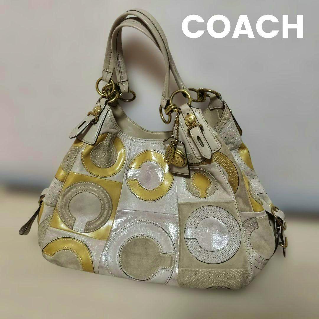 Coach shoulder bag with cream and yellow circular inlaid C patchwork, double handles, and gold hardware on a neutral background.