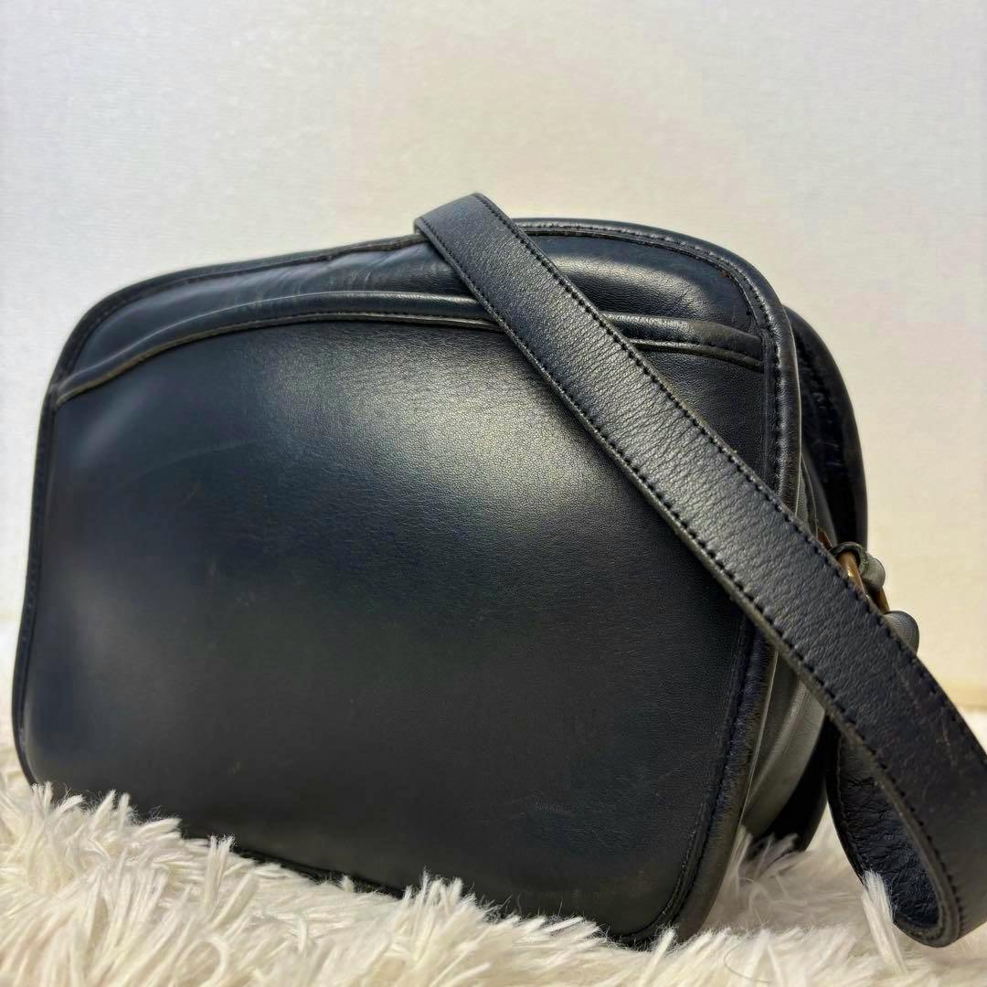Black leather COACH shoulder bag with its strap draped across the front.