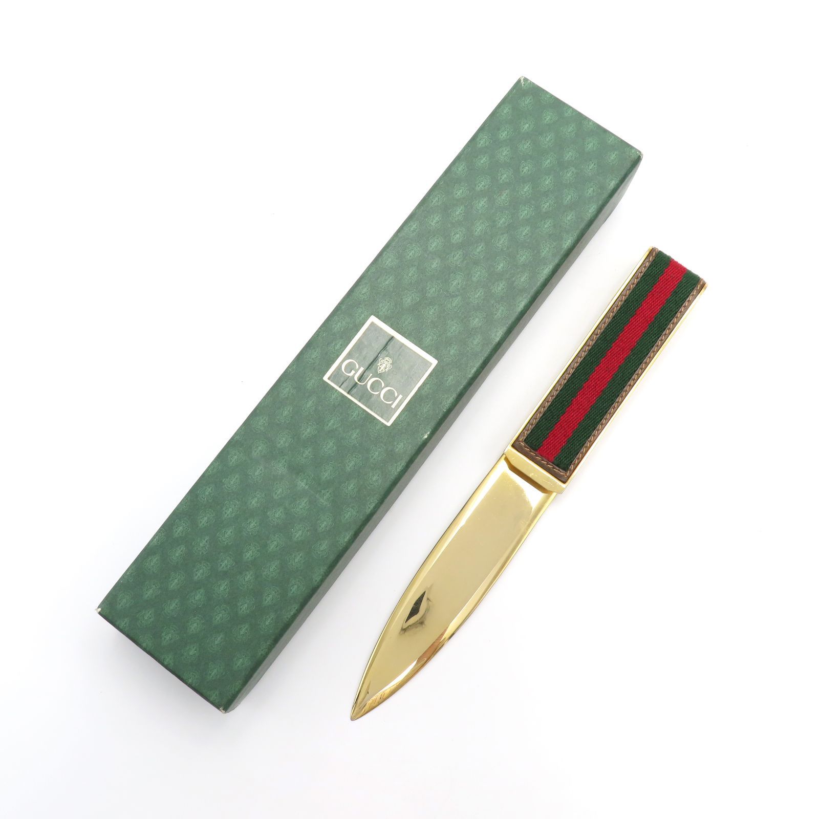 Gold-tone Gucci paper knife with a green and red striped handle next to a green Gucci box.