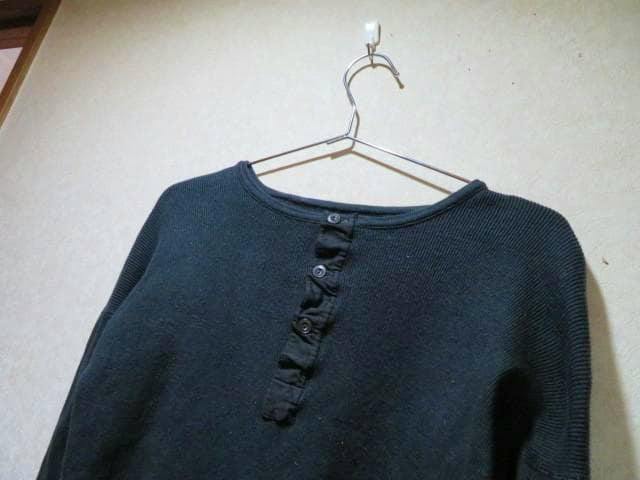 Black long-sleeve Henley-neck shirt hanging on a hanger, showing the upper front and button placket.