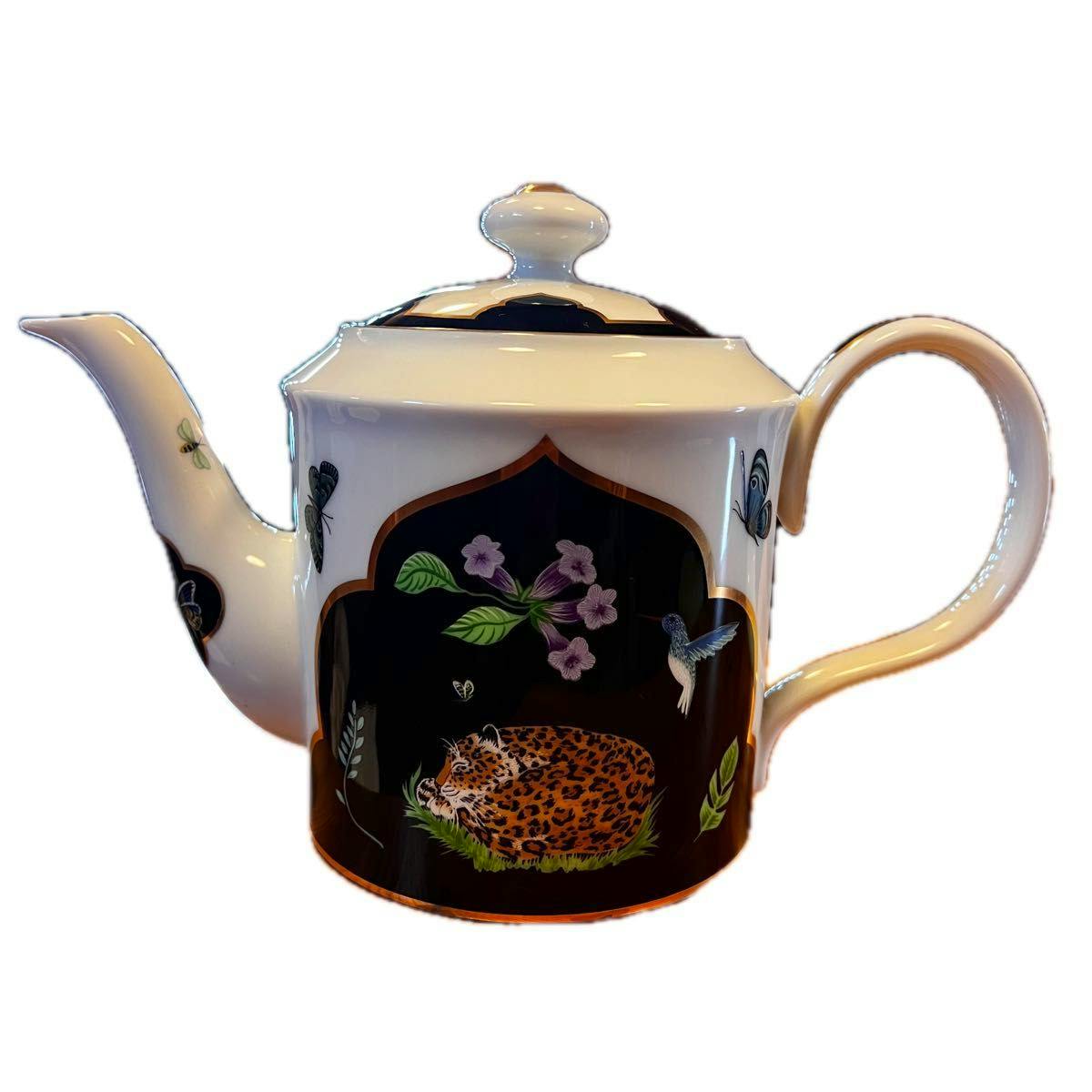 White ceramic teapot with lid, spout and handle, decorated with a black panel showing a sleeping jaguar, flowers and a hummingbird.