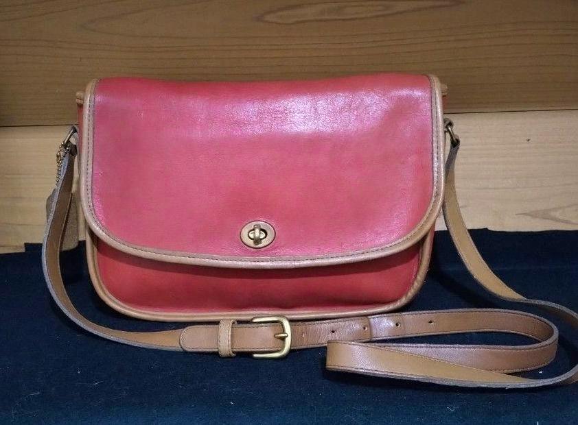 Front view of a red and tan bicolor Coach City shoulder bag with a flap and turn-lock closure.