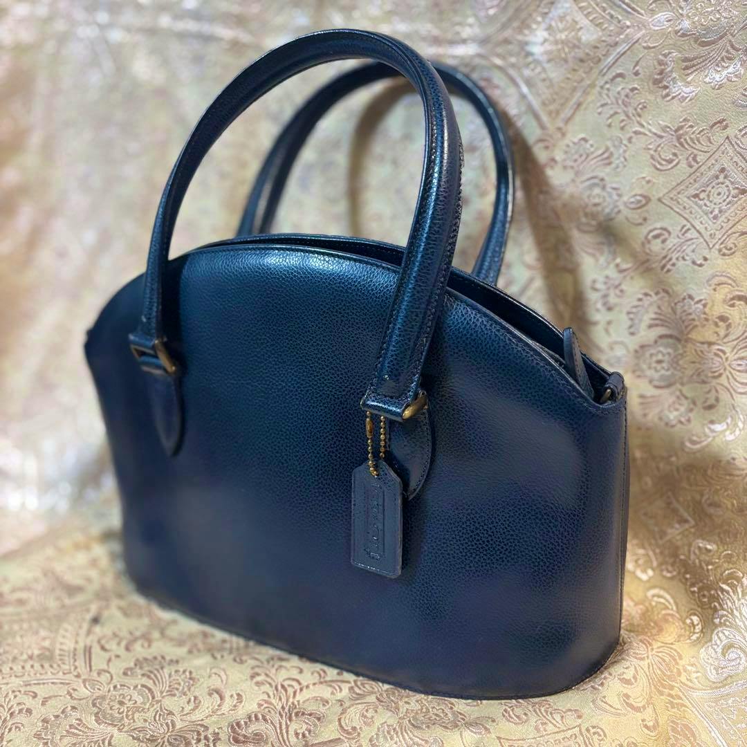 A navy Old Coach Madison 4408 leather handbag photographed on a patterned fabric background.
