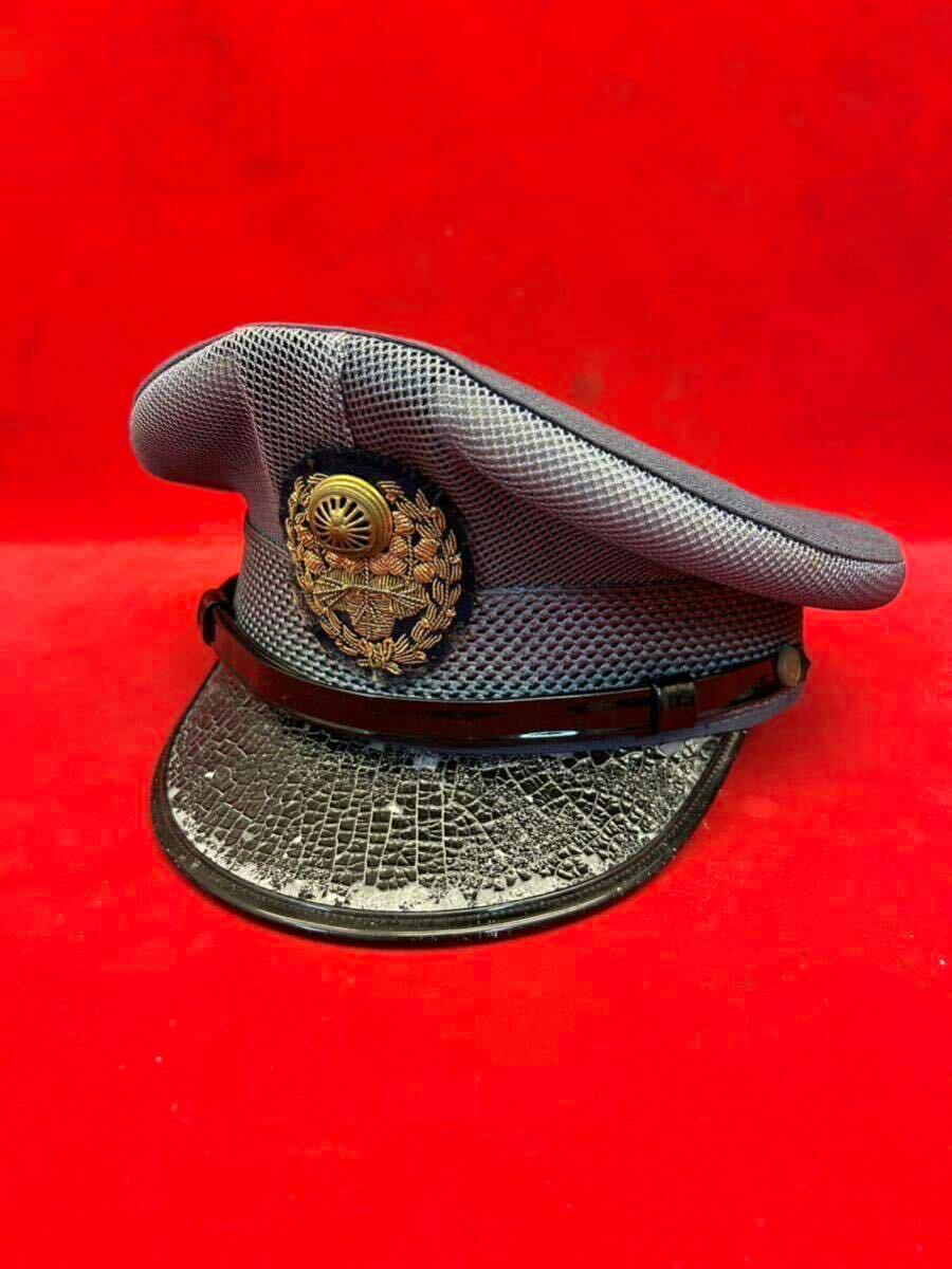 Gray Japan National Railways (railway police) peaked cap with a gold emblem and cracked black visor on a red background.