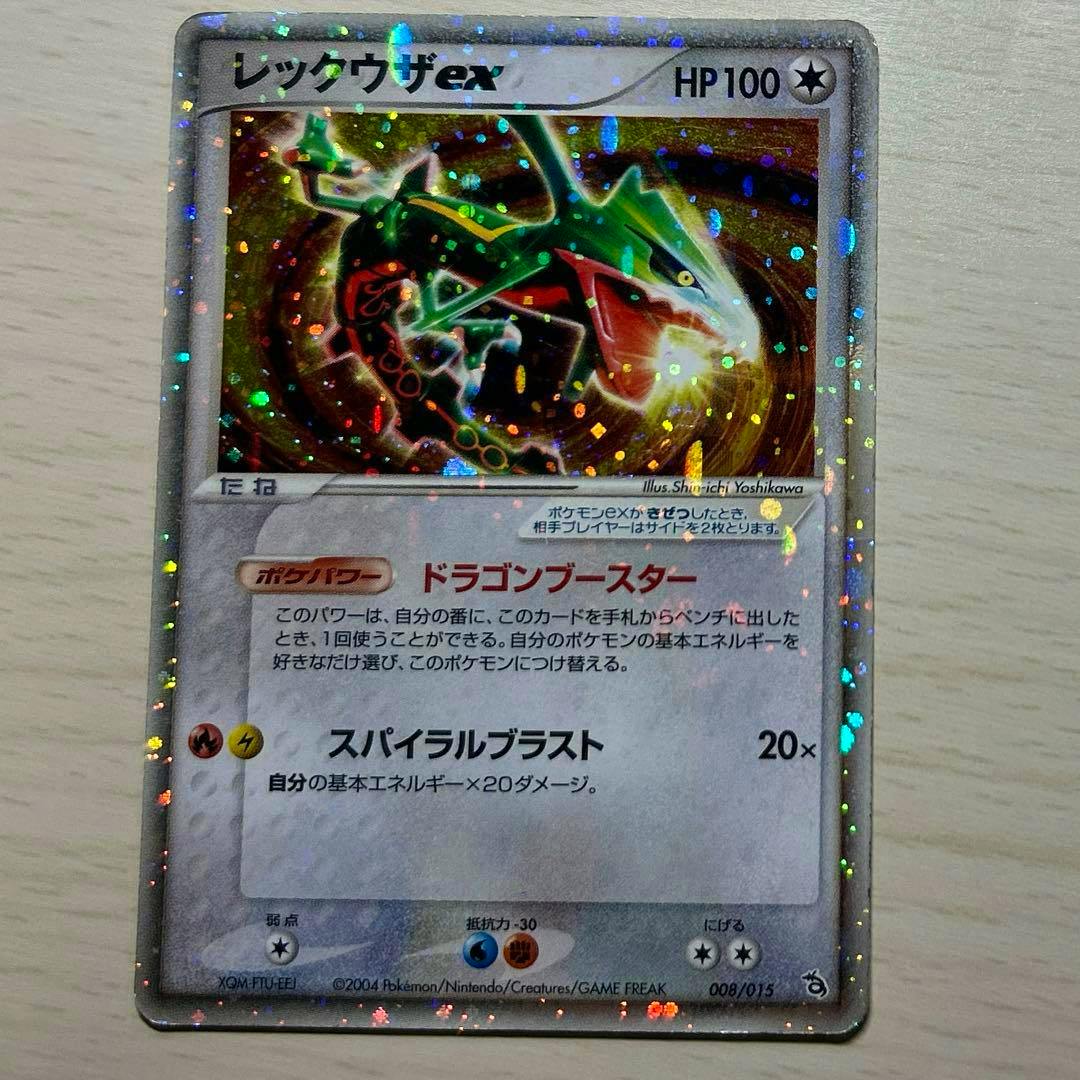 Front of a holographic レックウザ trading card (Japanese text, HP100) on a light surface.