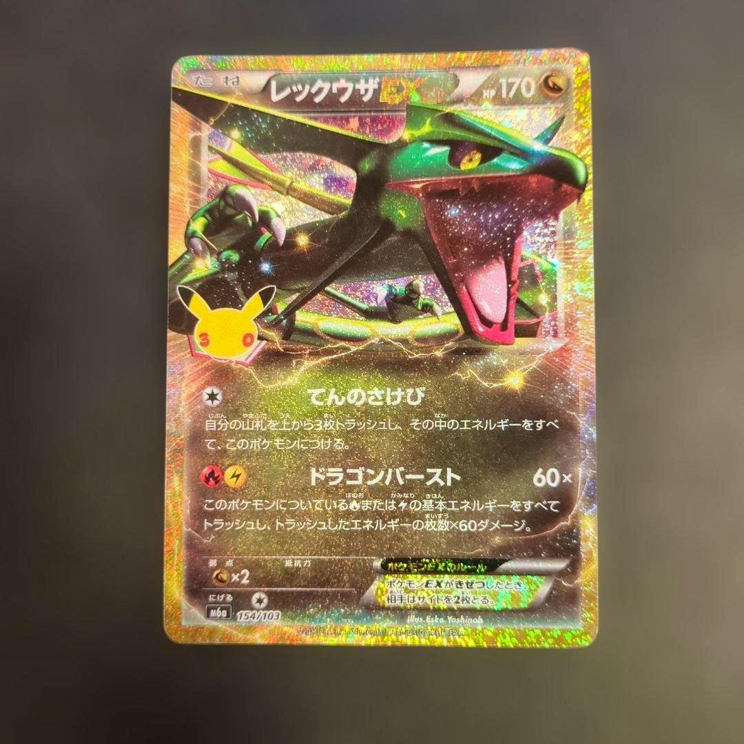 Front of a holographic レックウザEX Pokémon trading card placed on a dark background.