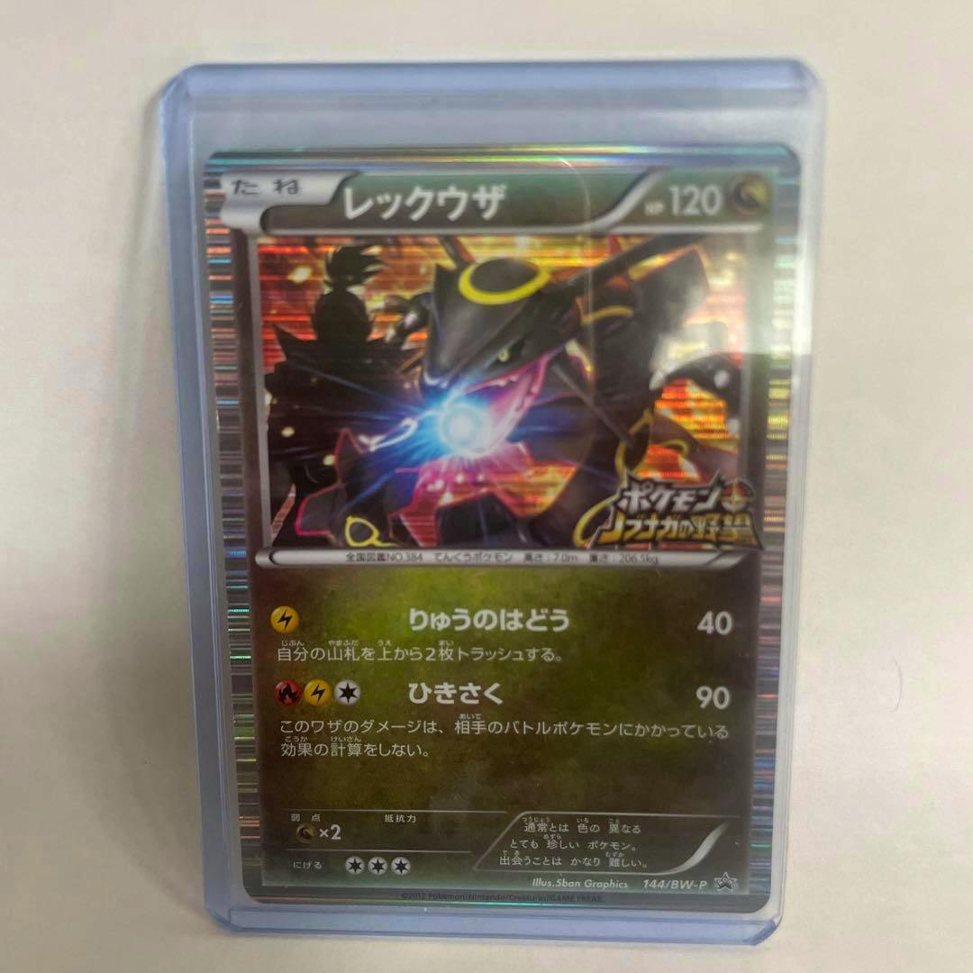 Front of a holographic レックウザ (Rayquaza) Pokémon trading card in a protective sleeve, showing Japanese text and artwork.