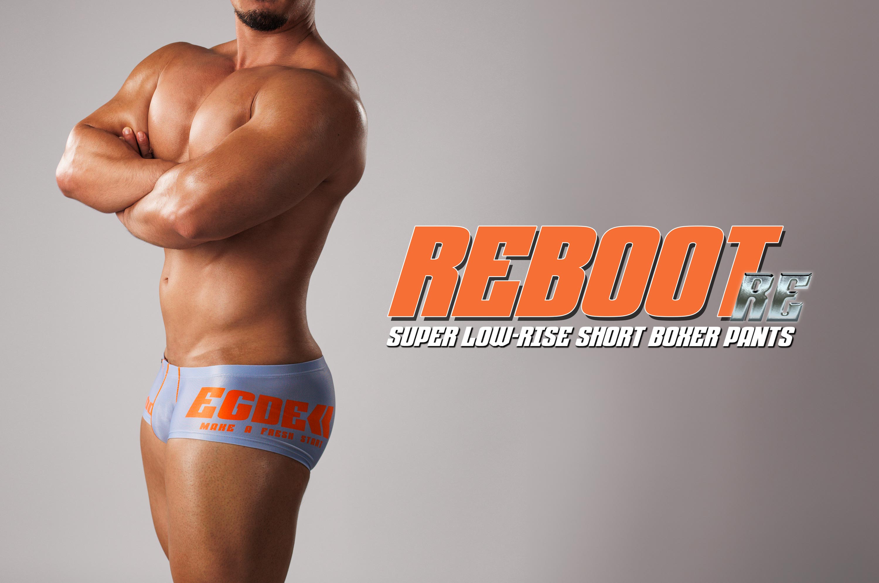 Side view of a male model wearing REBOOT super low-rise short boxer pants with a large REBOOT logo overlay.