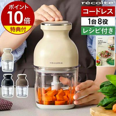 Beige recolte cordless Capsule Cutter food processor on a countertop with chopped carrots inside and hands holding the unit.