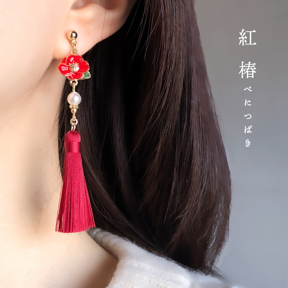 Close-up of an earlobe wearing a red camellia mini tassel earring with a small pearl bead.