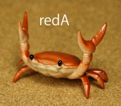 Red-toned plastic crab pen holder figure on a textured surface with the text 'redA' visible.