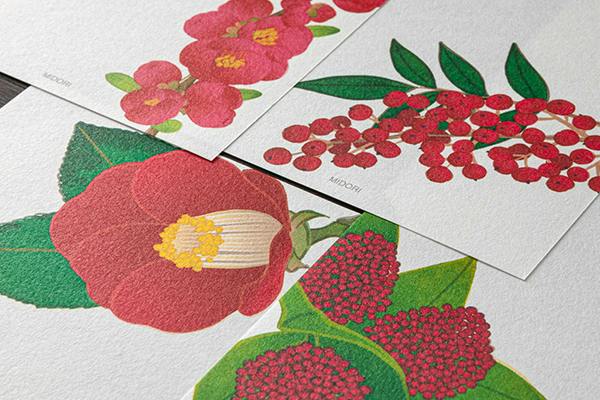 Close-up photo of the letter pad showing red winter floral and berry illustrations on printed sheets.