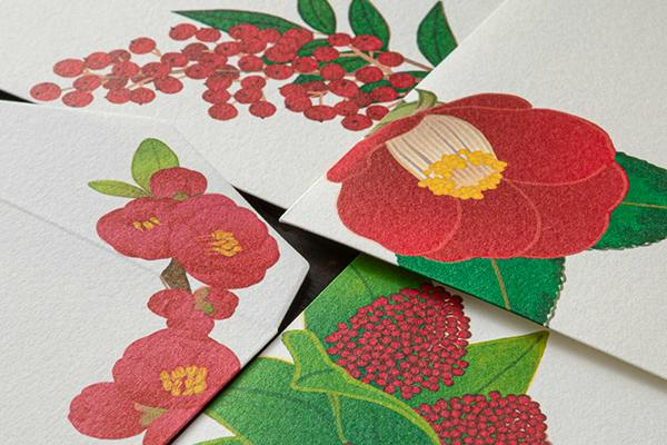 Close-up photo of envelopes showing red winter floral patterns printed on the paper.
