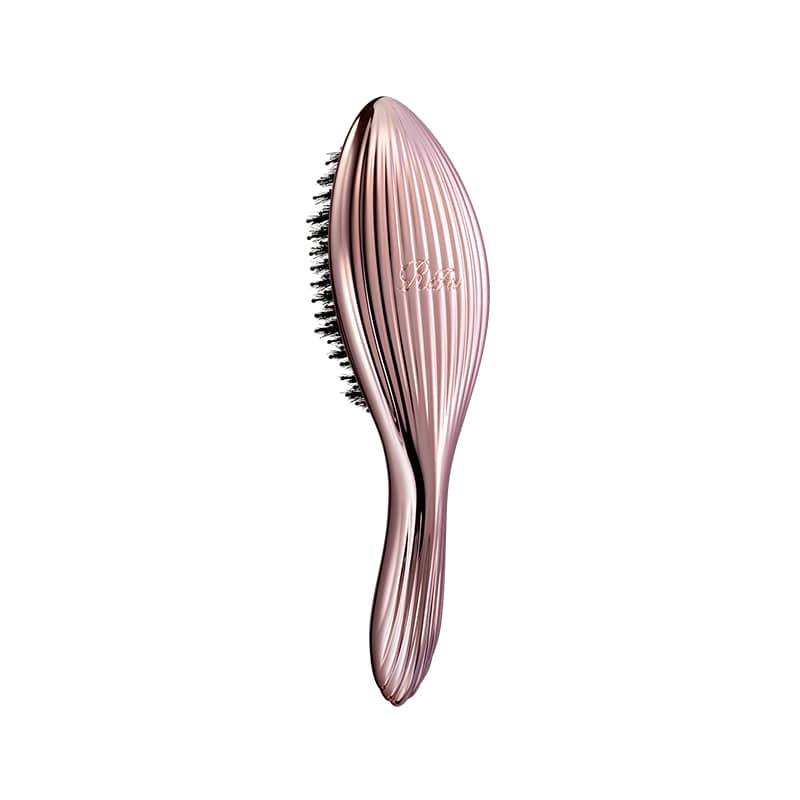 A rose-gold hair brush with a ribbed elongated handle and visible black bristles shown against a white background.