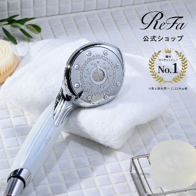 Chrome-and-white ReFa FINE BUBBLE PURE showerhead resting on a white towel on a tiled surface.